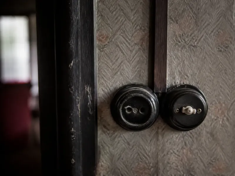 Ancienne prise sans terre et interrupteur rotatif en bakélite sur un mur de maison